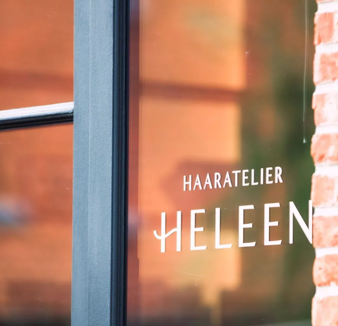 Logo van Haaratelier Heleen op een raam