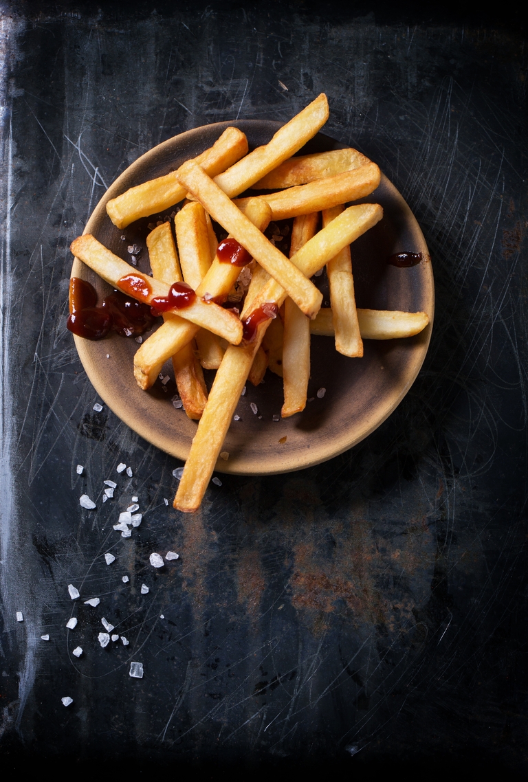 frietjes met zout en ketchup op donkere achtergrond