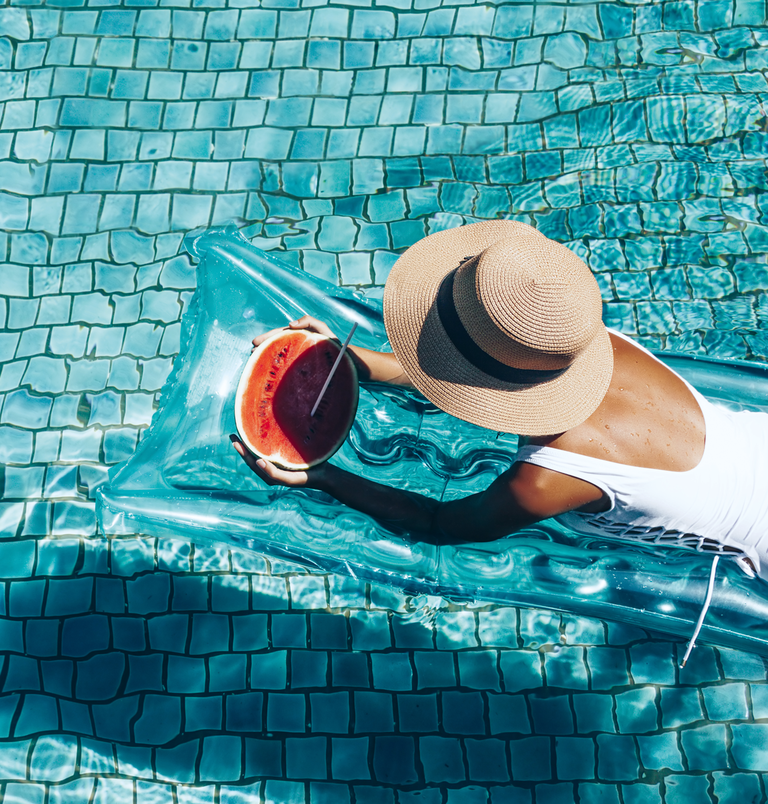 vrouw op een luchtmatras in het zwembad met watermeloen